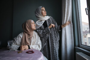 Jalabiya and abaya waring women looking on the window